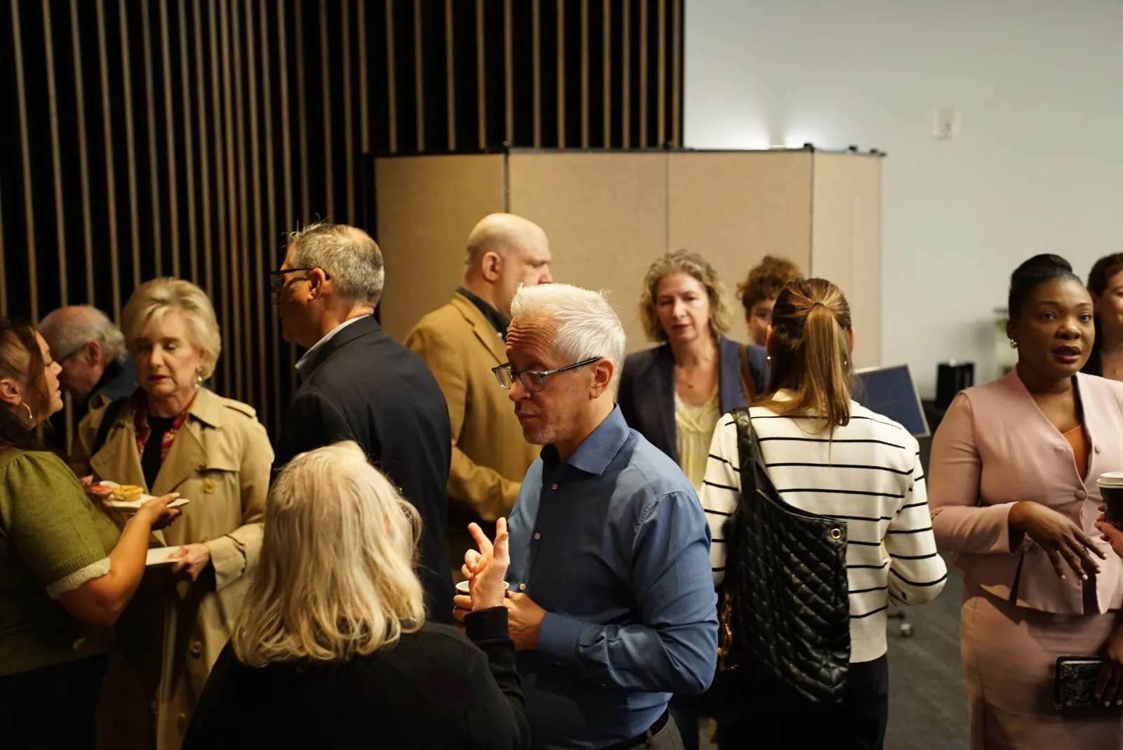 Guests standing and talking in a meeting room at the senior living round table at Frank Residences in San Francisco